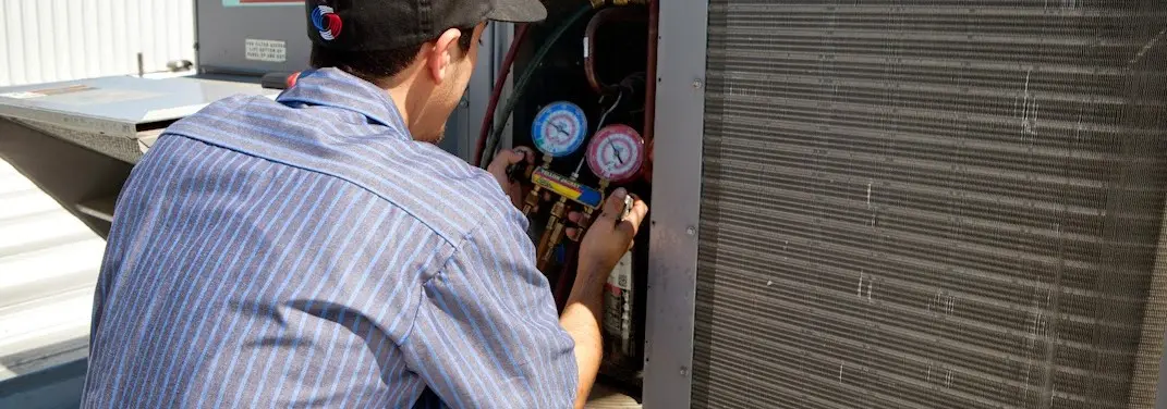 HVAC technician servicing a condenser unit in Riverdale