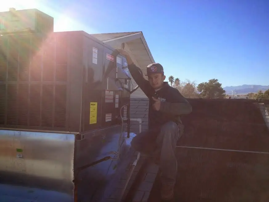 HVAC technician performing AC Tune-Up on a rooftop unit in Riverdale